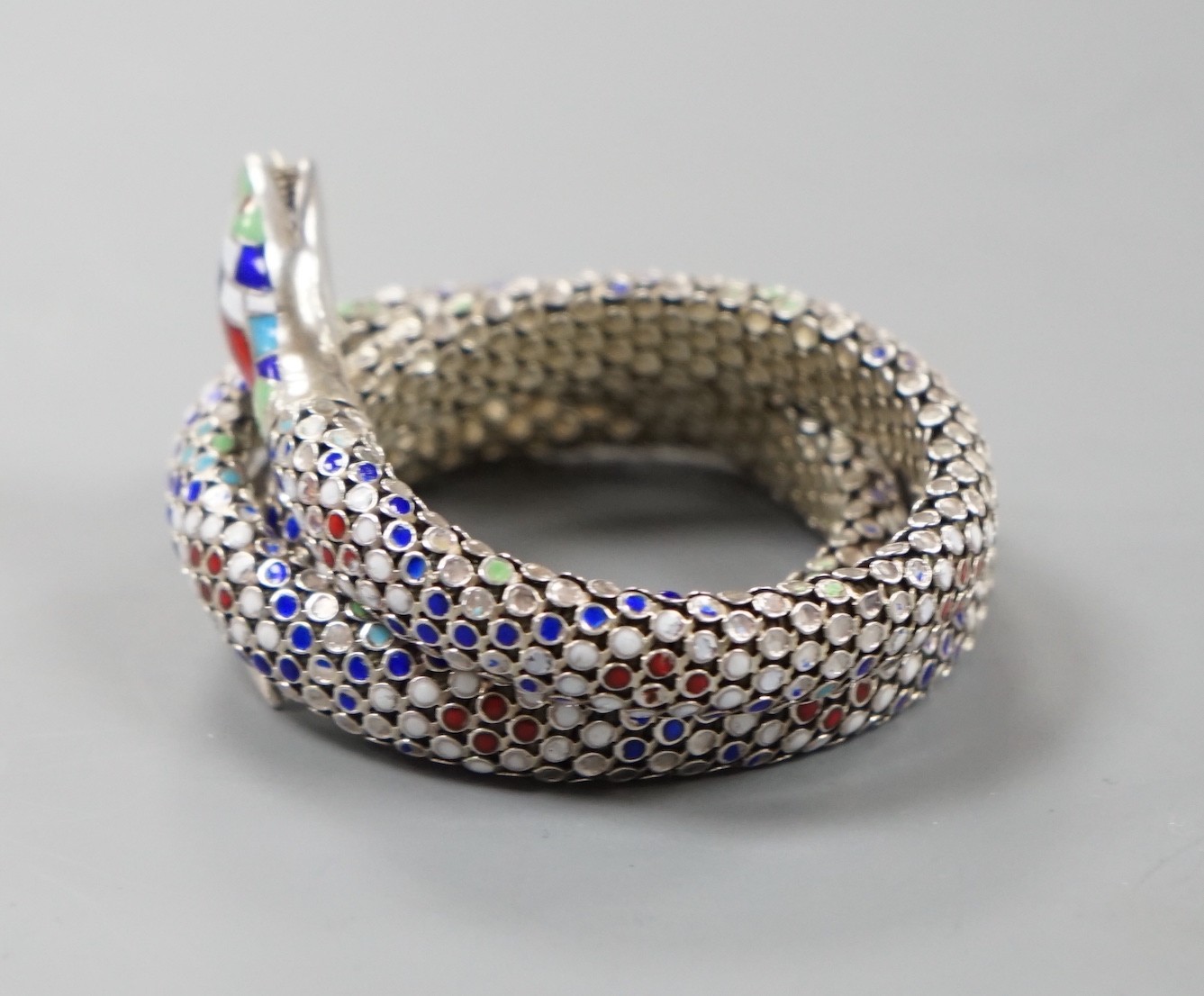 A continental 935 white metal and polychrome enamel set coiled serpent bangle.